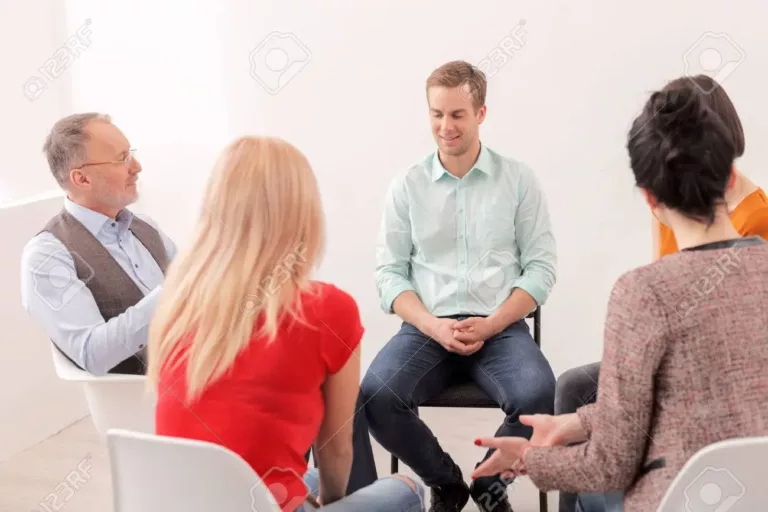 57363091-attractive-young-man-is-sharing-his-feelings-with-psychologist-and-group-he-is-sitting-and-smiling-w