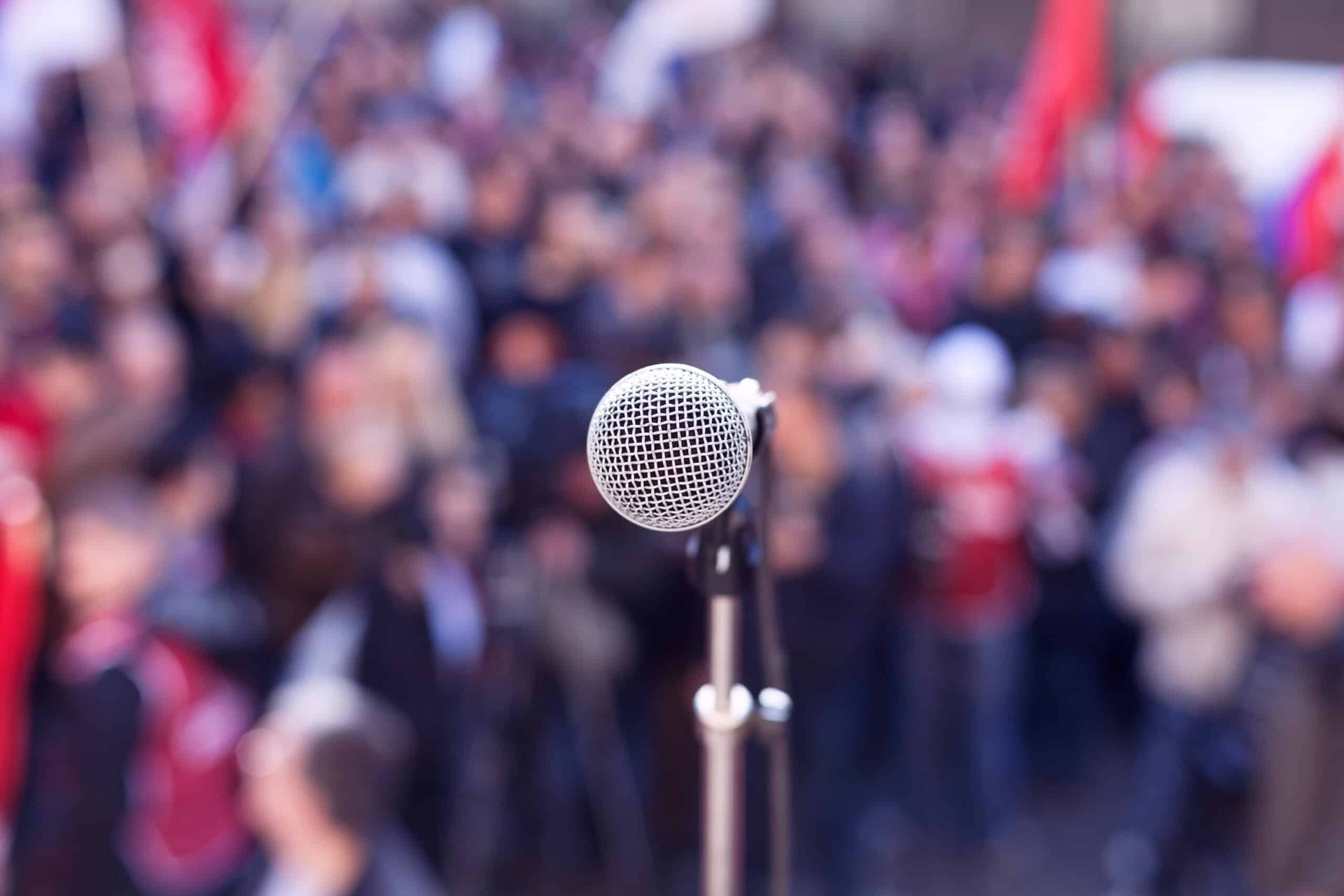 Political,Protest.,Demonstration.,Microphone,In,Focus,Against,Blurred,Crowd.