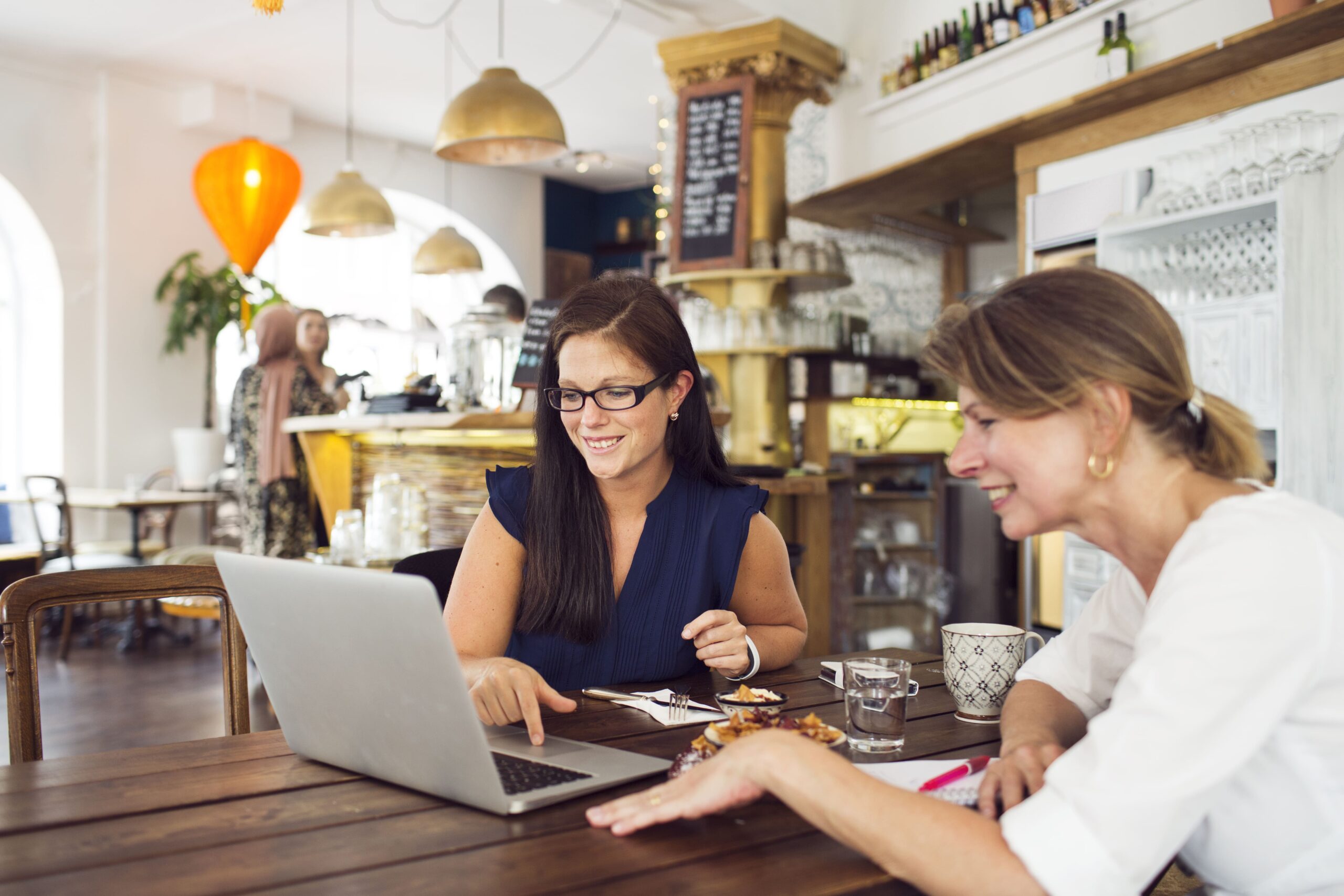 businesswomen-using-laptop-during-lunch-in-restaur-2024-10-17-15-04-32-utc-min